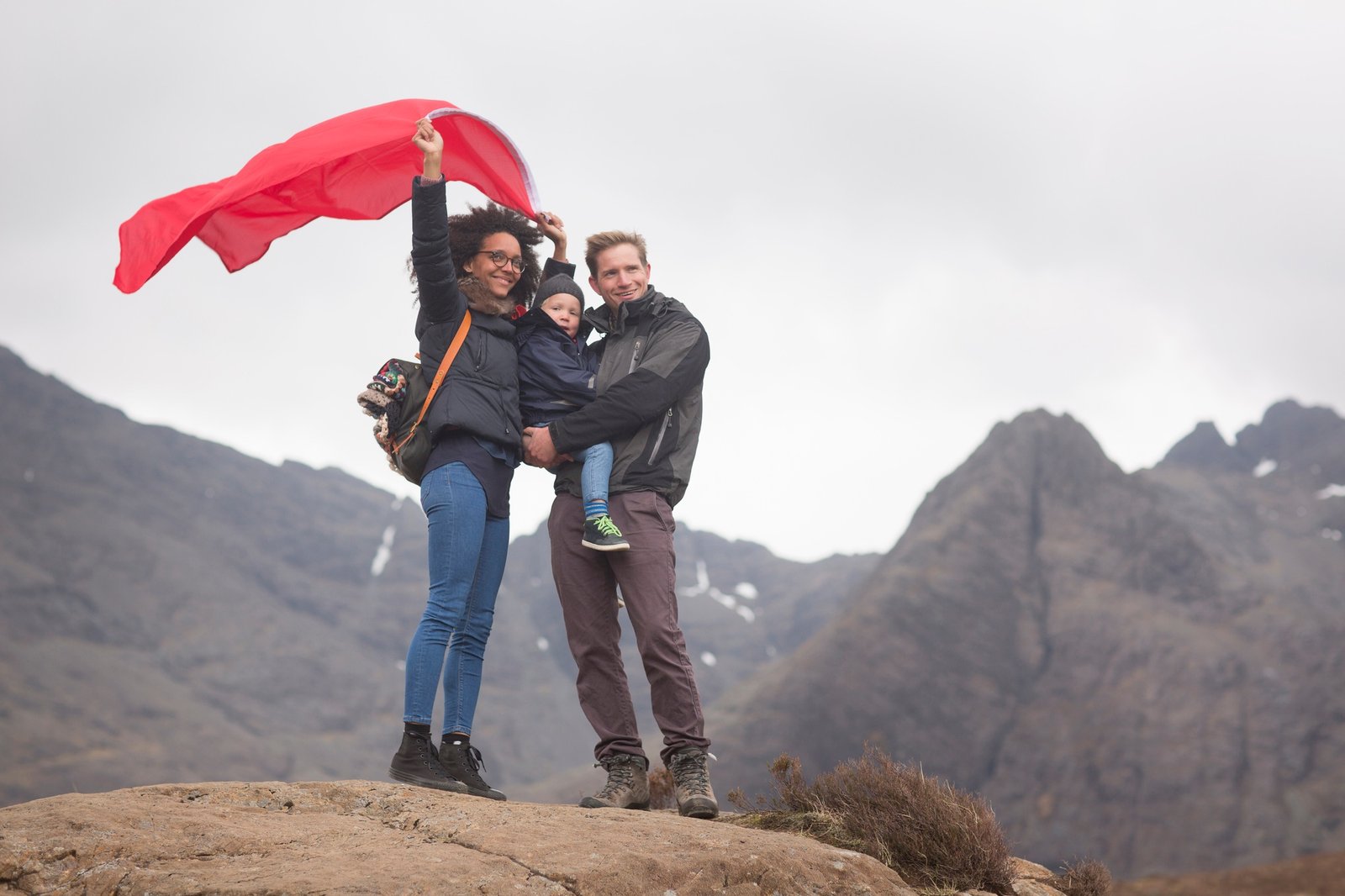 Family holding red flag in mountains, Fairy Pools, Isle of Skye, Hebrides, Scotland