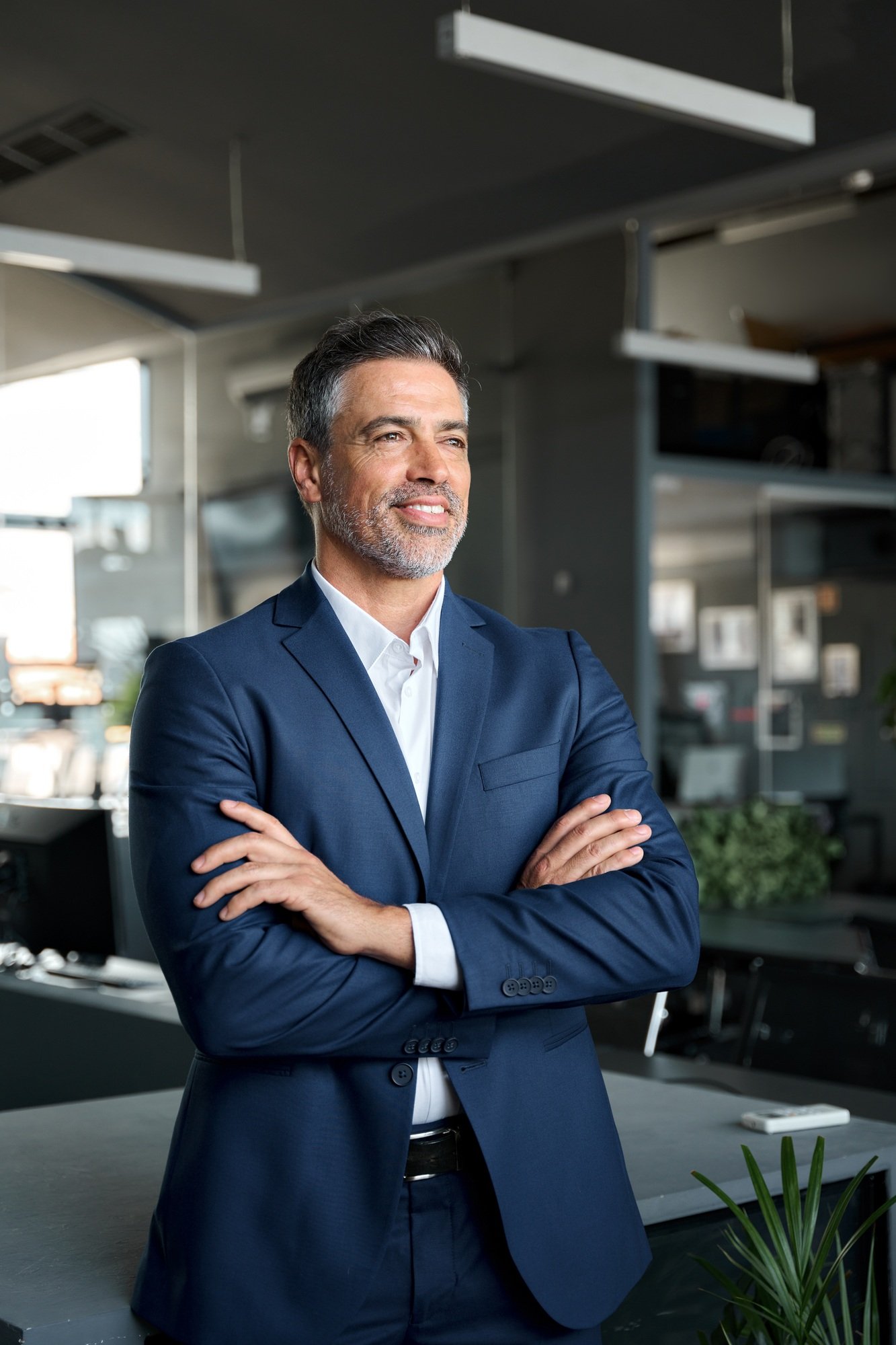 Happy proud mature business man ceo standing in office arms crossed thinking.