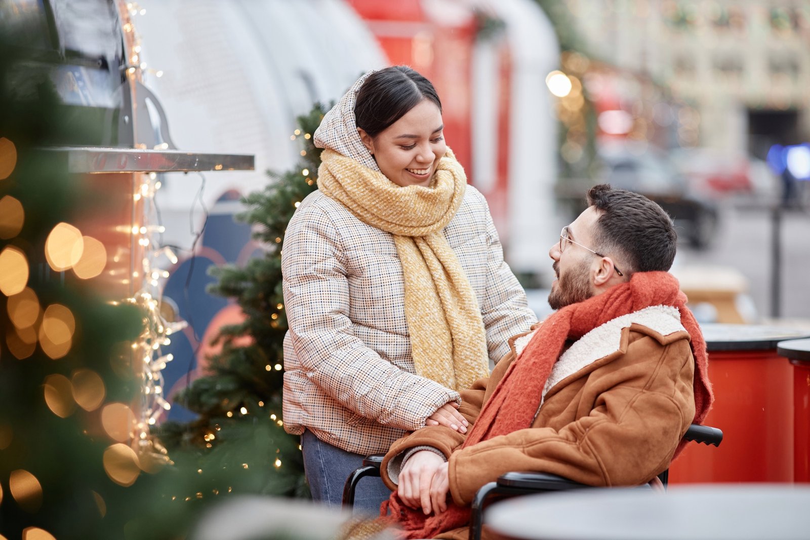 Young woman smiling at partner with disability having fun in Christmas market